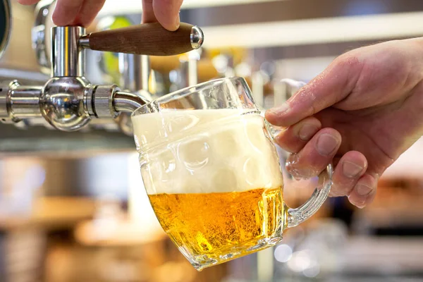 Een man giet tocht lager bier in een kuiltje glas mok in een mo — Stockfoto