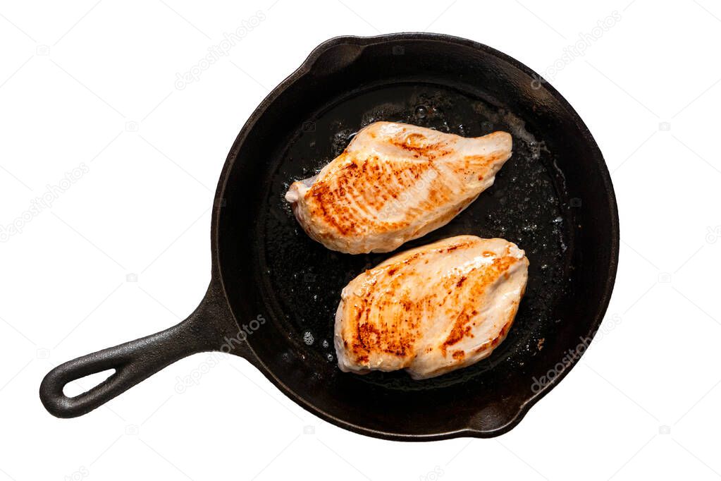 Two whole chicken breasts roasting in cast iron pan isolated on 