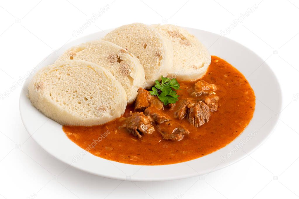 Beef goulash with bread dumplings and parsley garnish on white c