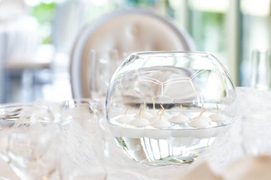 Beyaz düğün masasının ayrıntıları ve yüzen mumlar.