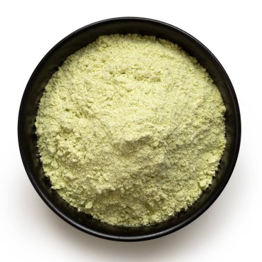 Beyaz üzerine izole edilmiş siyah seramik kasede kurutulmuş yeşil bezelye unu. Üst görünüm.