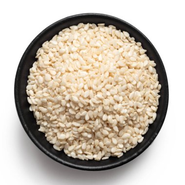 Siyah bir seramik kasede soyulmuş susam tohumları beyaza izole edilmiş. Üst görünüm.