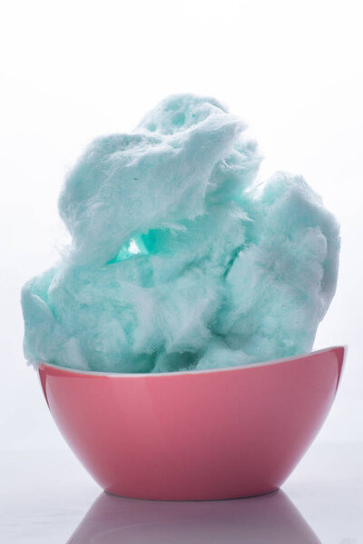 Голубая свеча из хлопка в миске на белом фоне
