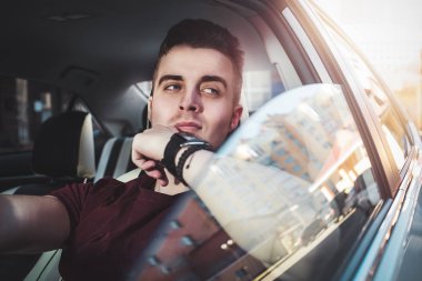 İyi yolculuklar. Arabada oturan yakışıklı bir genç resmi..