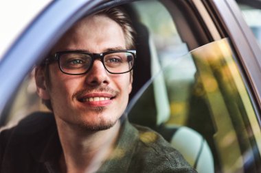 İyi yolculuklar. Arabada oturan yakışıklı bir genç resmi..