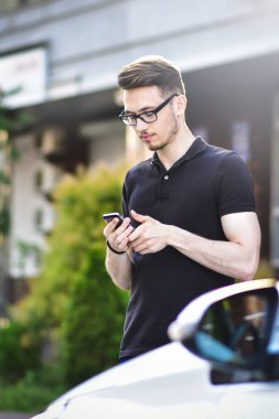 Telefon arabasıyla yakınındaki bir yakışıklı gülümseyen beyaz iş adamı portresi.