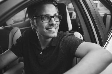 İyi yolculuklar. Arabada oturan yakışıklı bir genç resmi..