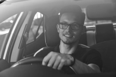 Bir arabada oturan ve direksiyon tutan yakışıklı adam.