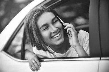 Telefonu arabada arka koltukta otururken gülümseyen güzel kadın.