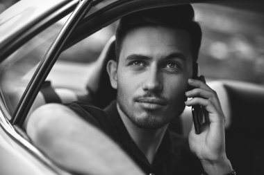 Yakışıklı adam arabanın arka koltuğunda oturmak ve bir telefon kullanma.