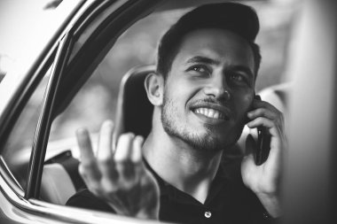 Yakışıklı adam arabanın arka koltuğunda oturmak ve bir telefon kullanma.