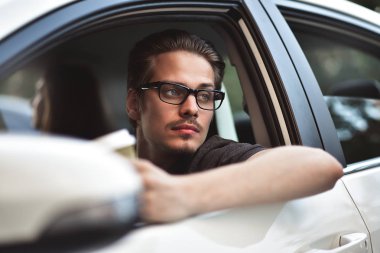 İyi yolculuklar. Arabada oturan yakışıklı bir genç resmi..