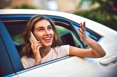 Telefonu arabada arka koltukta otururken gülümseyen güzel kadın.