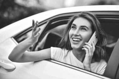 Telefonu arabada arka koltukta otururken gülümseyen güzel kadın.