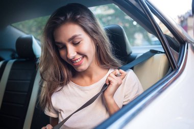 Telefonu arabada arka koltukta otururken gülümseyen güzel kadın.