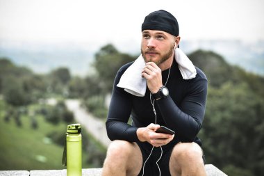 Havlu kontrol ile kas sakallı atlet yakılan kalori smartphone iyi egzersiz oturum sonrası Şehir Parkı üzerinde.