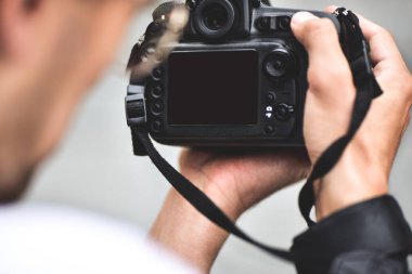 Dijital tek lensli refleks kamera ellerinde. Fotoğrafçı el kamerasıyla ateş ediyor. Erkek fotoğrafçı, stok fotoğrafçılığı için fotoğraf çekiyor. Erkek eller kamerayı yakın çekimde tutun.