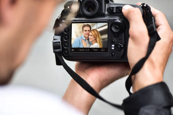 Digital single-lens reflex camera in hands. Photographer shooting hands close up. Man photographer makes photos for stock photography. Male hands hold the camera close-up