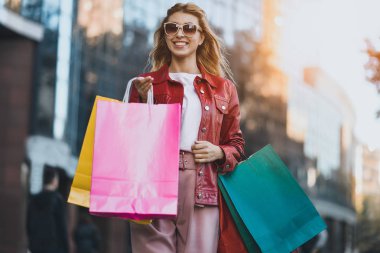 Dışında sokak holding alışveriş torbaları yürüyen kadın alışveriş. Mutlu street yürüyüş alışveriş sonra gülümseyerek shopper