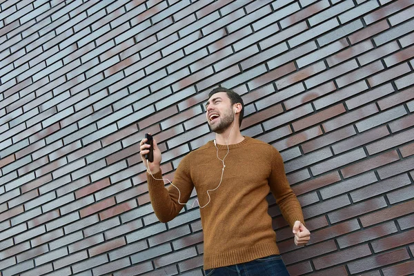 Портрет Улыбающегося Человека Наушниками Сотовым Телефоном Стоящего Кирпичной Стены — стоковое фото