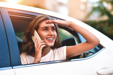 Telefonu arabada arka koltukta otururken gülümseyen güzel kadın.