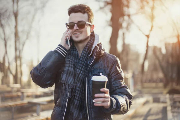 Beyaz adam sokakta cep telefonu bakıyor.