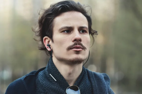 Guapo joven rizado hombre escuchando música y piensa en algo importante para él — Foto de Stock