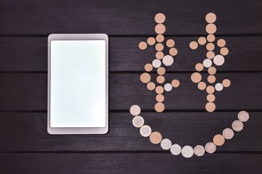 Finansal başarı kavramı. Akıllı Telefon ve Madeni Paralar Masada Gülen Yüz emojisi oluşturdu. Şanslı bir gün. başarı iş. ücretsiz copyspace. Teknoloji paradır.