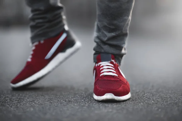 Sports red sneakers close-up on asphalt. Legs and shoes from the lower angle.