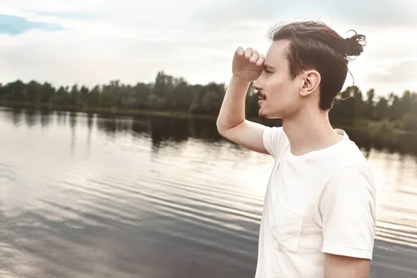 Hombre Disfruta de una hermosa vista y mira a la distancia cerca de un lago y un bosque. Verano. primavera. naturaleza . — Foto de Stock