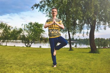 Fitness adam parkta izole bir bacak üzerinde egzersiz yapıyor. Doğa, yoga ve meditasyon konseptinin tadını çıkarın. manevi Practices. Zen