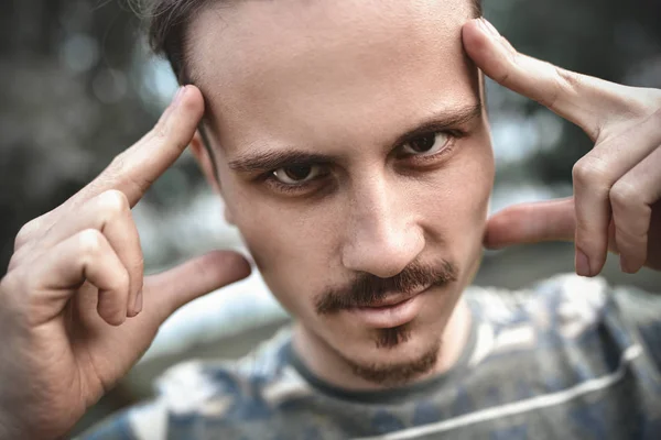 Jogos mentais e poder cerebral. conceito de habilidades mentalistas e cognitivas. homem concentrando e segurando dedos indicadores em templos. jovem barbudo cara retrato no fundo azul . — Fotografia de Stock