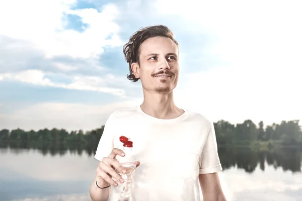 젊은 남자는 호수와 숲 배경에 대해 신선한 물을 마신다. 여름 갈증. 사람 원 에 마셔 — 스톡 사진