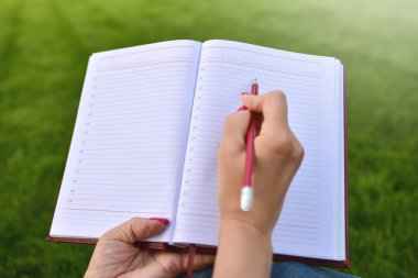 genç kadın yazma not defterinde park, kavramı eğitim ve bilgi kapatın