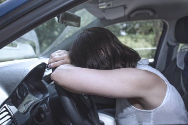 Direksiyondaki genç bayan sürücü, aşırı yorgun, tehlikeli bir durumda araba kullanırken uykuya dalıyor - yol güvenliği kavramı