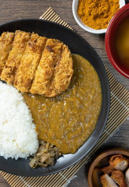 Tonkatsu Curry Rice (Japon usulü kızarmış domuz pirzolası ve köri pilavı) kareage (Japon usulü kızarmış tavuk) ile servis edilir. Ahşap arka planda üst manzara. düz yat.