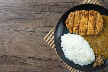 Tonkatsu Curry Rice (Japon usulü kızarmış domuz pirzolası ve köri pilavı) kareage (Japon usulü kızarmış tavuk) ile servis edilir. Tahta arkaplanda fotokopi alanı olan üst görünüm. düz yat.
