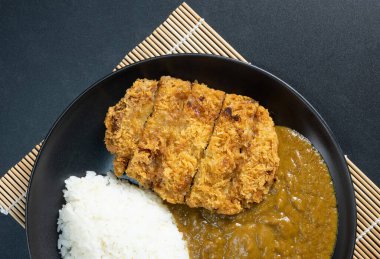 Tonkatsu köri pilavı (Japon kızarmış domuz pirzolası ve köri pilavı). Siyah arkaplanda üst görünüm. düz yat.