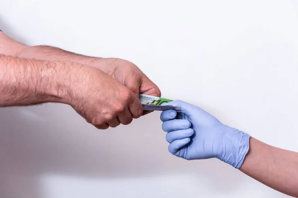 Χέρι του ασθενούς δίνοντας χάρτινο νόμισμα σε γυναίκα γιατρό σε λευκό φόντο — Φωτογραφία Αρχείου