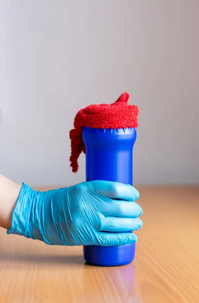 V ruce drží modrou sklenici čisticího prostředku a červený hadr na čištění — Stock fotografie
