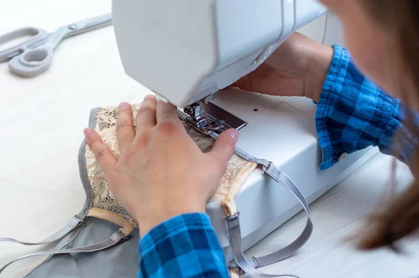 Mavi kareli gömlekli neşeli bir terzi atölyesinde çalışıyor. Yakın plan, Lacy 'nin kadın iç çamaşırlarını dikiyor..