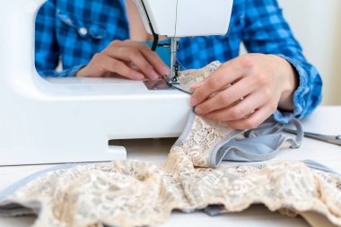 Mavi kareli gömlekli neşeli bir terzi atölyesinde çalışıyor. Yakın plan, Lacy 'nin kadın iç çamaşırlarını dikiyor..