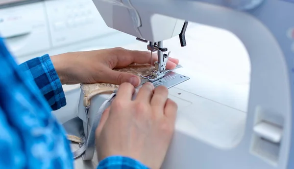 Una costurera alegre con una camisa de cuadros azules está trabajando en su taller. primer plano, ella está cosiendo ropa interior de encaje de las mujeres . —  Fotos de Stock