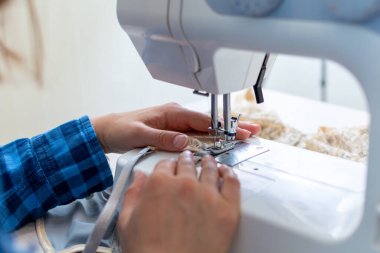 Mavi kareli gömlekli neşeli bir terzi atölyesinde çalışıyor. Yakın plan, Lacy 'nin kadın iç çamaşırlarını dikiyor..