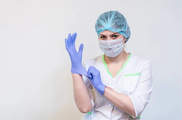 A young woman doctor puts a blue medical glove on her hand. Close up. — Stock Photo, Image
