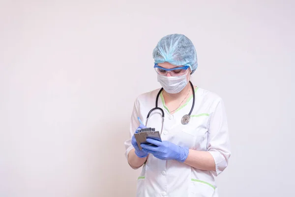 A young female doctor makes notes on a tablet — Stock Photo, Image