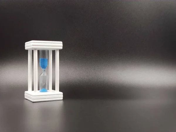 Bílé přesýpací hodiny s modrým pískem, zobrazující poslední vteřinu nebo minutu. koncept plynutí času. S prostorem pro kopírování — Stock fotografie