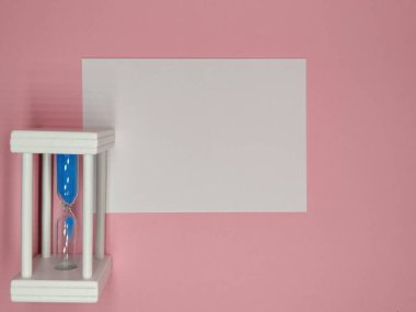 Pembe bir arka planda, bir kum saati ve fotokopi alanı olan beyaz bir çarşaf..