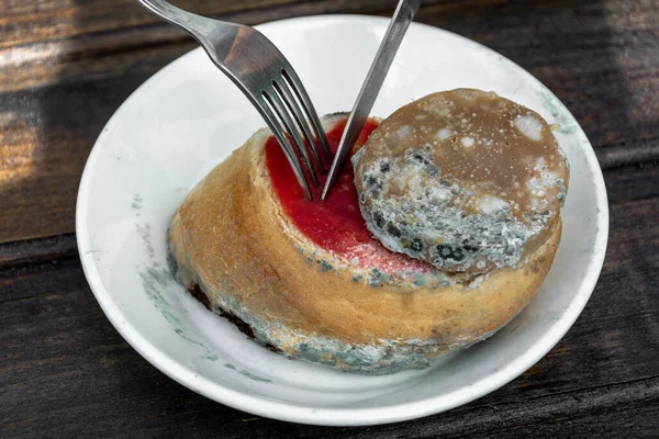 Çürümüş, küfle kaplı bir sandviçi kesen çatal ve bıçağın yakın çekimi..