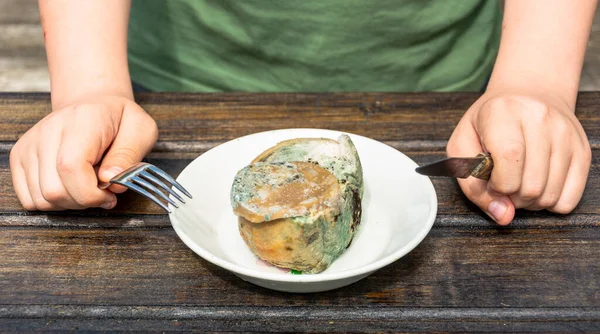 Primer plano de las manos de un hombre sosteniendo un tenedor y un cuchillo junto a un sándwich estropeado y mohoso . — Foto de Stock